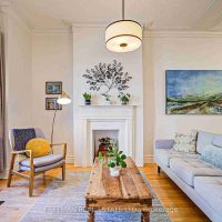 Living room with hardwood floors, original mouldings, and fireplace